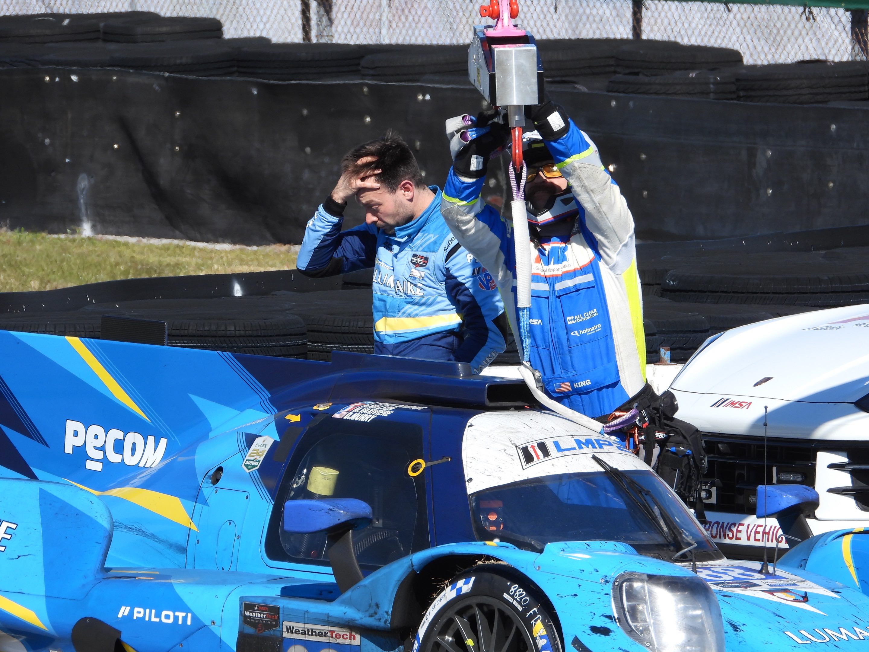 A race car driver looks on in dismay as a crew recovers his expired LMP2